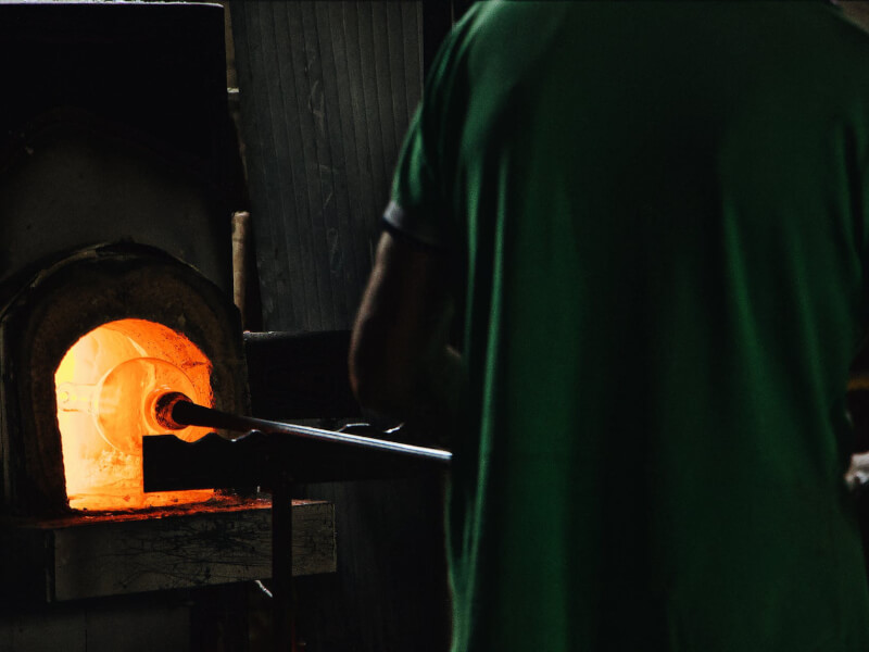 A man holding a glassblowing pipe